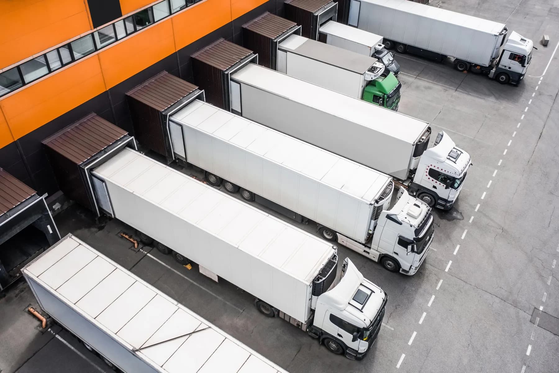 Weiße Sattelzüge an den Rampen eines Logistikzentrums, Luftaufnahme